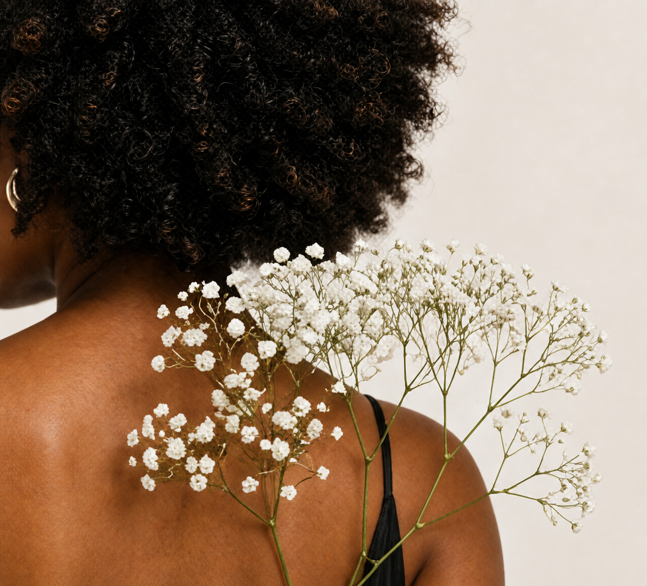 Black woman with natural hair and baby's breath flowers at her shoulder