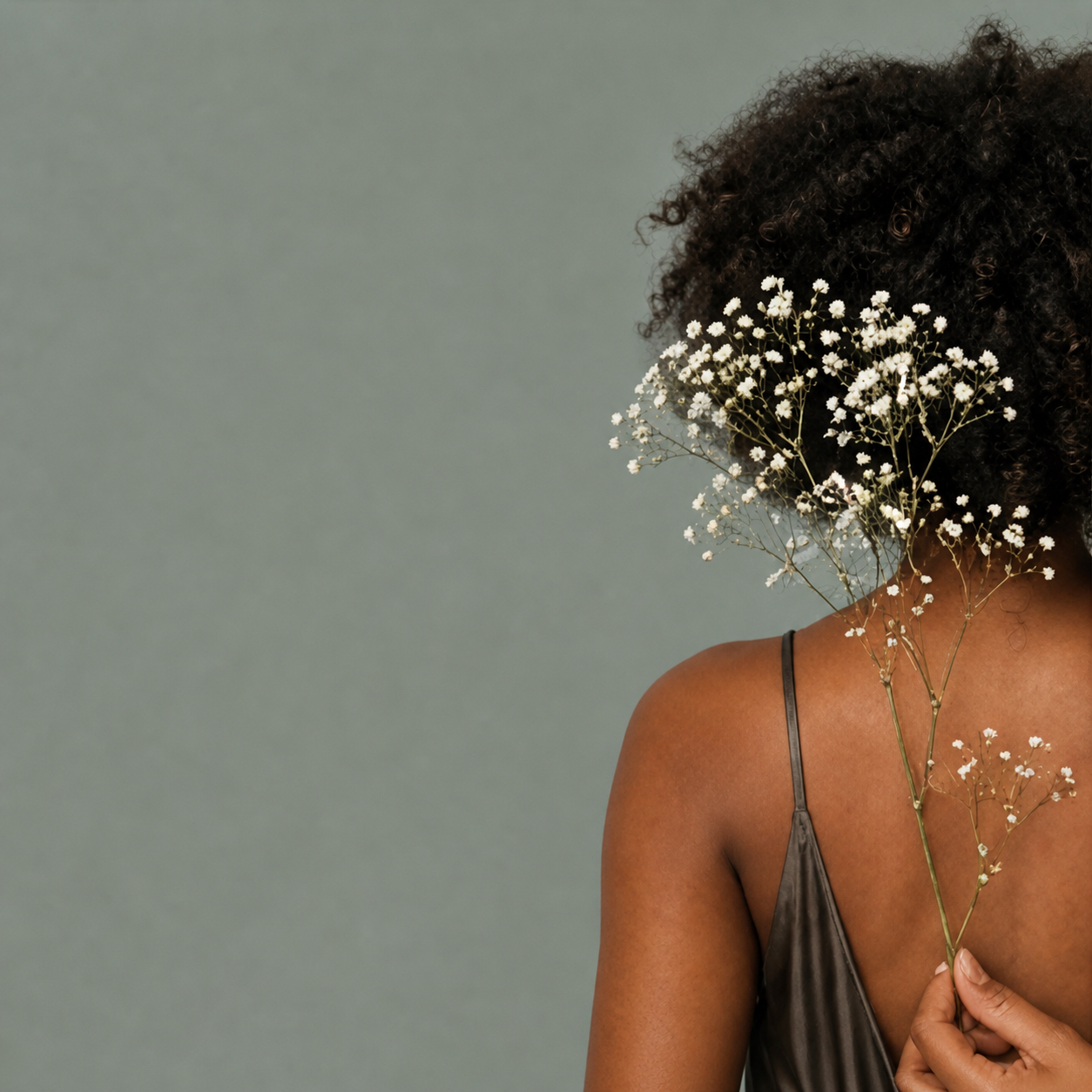 Black woman with baby's breath flowers held against her hair
